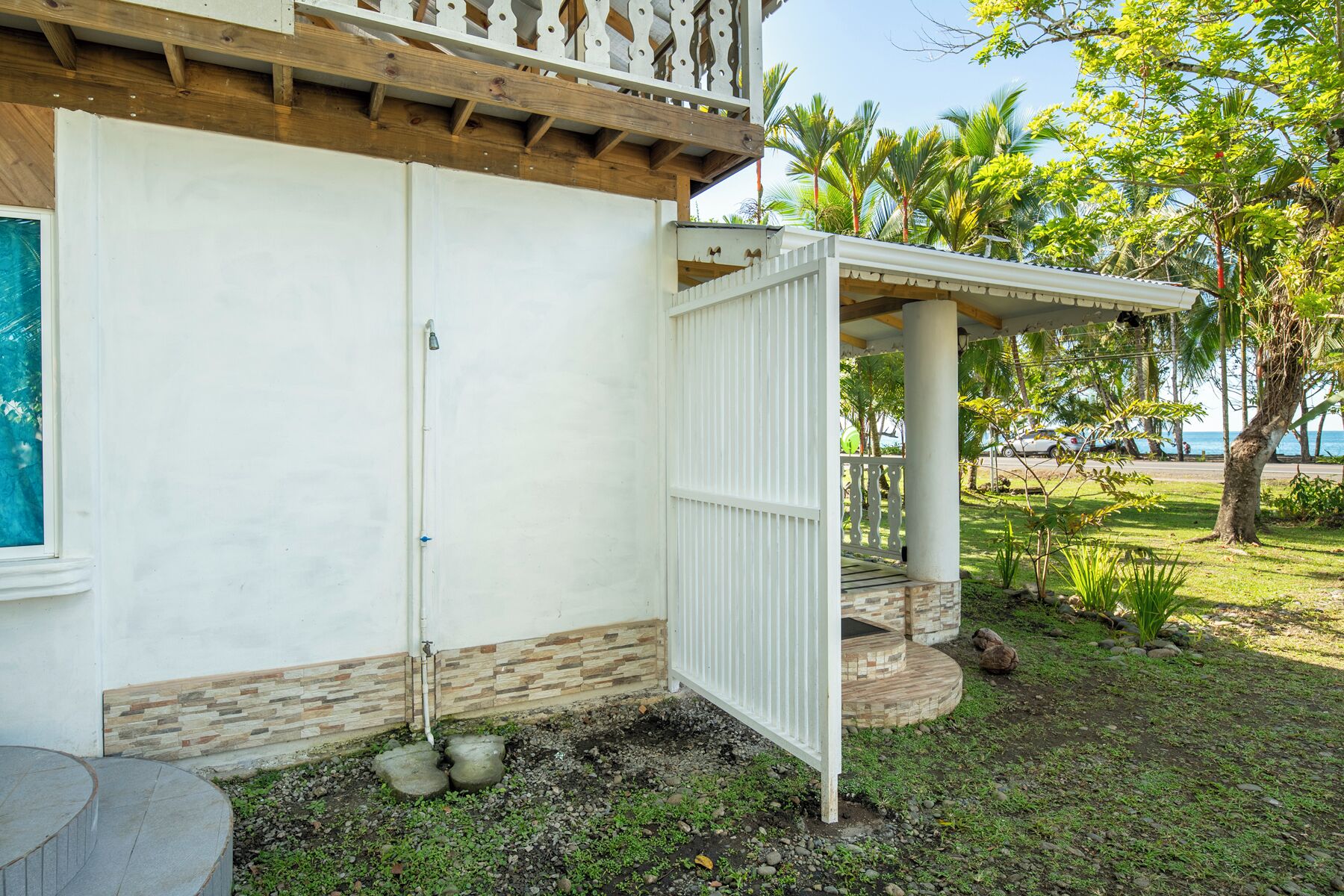 A house with a white exterior, a stone base, and a wooden balcony.