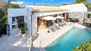 Une maison moderne dotée d’une piscine, d’un espace salon extérieur couvert et d’une chambre avec une porte coulissante.