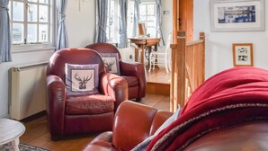 Een gezellige woonkamer met leren fauteuils, een eettafel en een rode deken.