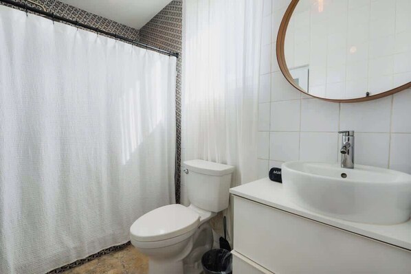 Un baño con inodoro, lavamanos y cortina de ducha.