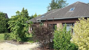 Une maison de plain-pied en briques, avec un toit en pente, une antenne parabolique et une petite fenêtre.