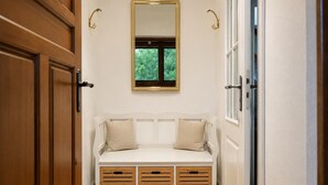 A white bench with storage drawers, a mirror above, and a window with greenery outside.
