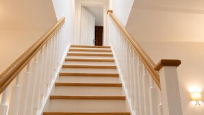 A staircase with wooden steps and white railings, leading to a door at the top.