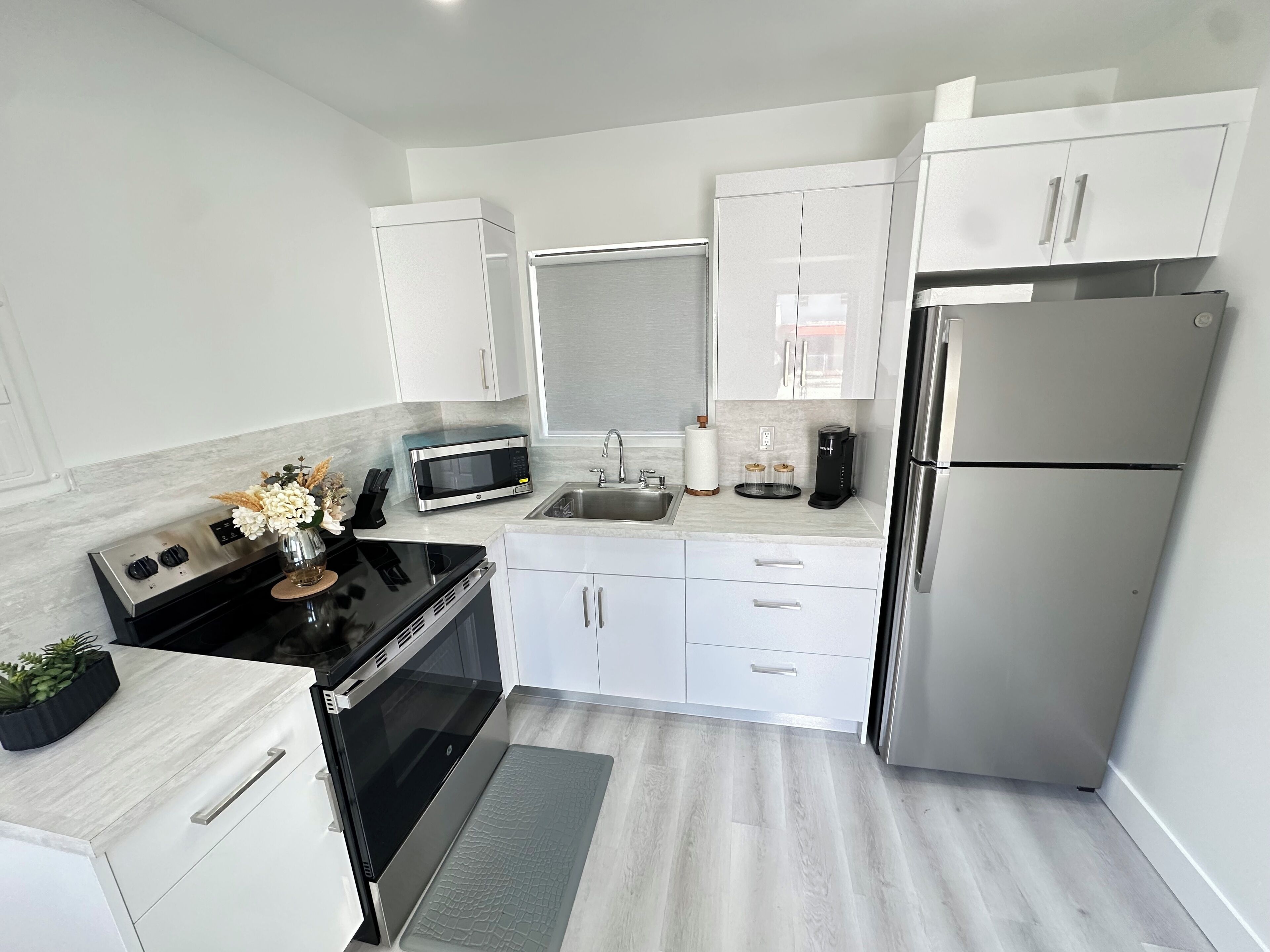 Una cocina moderna con gabinetes blancos, electrodomésticos de acero inoxidable y encimera negra.