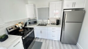 A modern kitchen with white cabinets, stainless steel appliances, and a black countertop. - Charming 1-bedroom apartment with AC, WiFi in vibrant Miami (Miami)