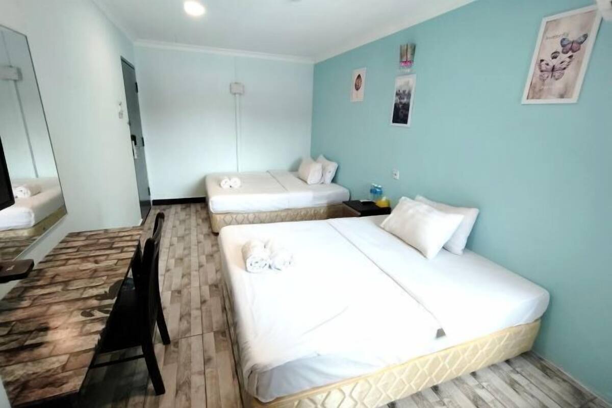 A hotel room with two beds, a wooden dining table, and a mirror.