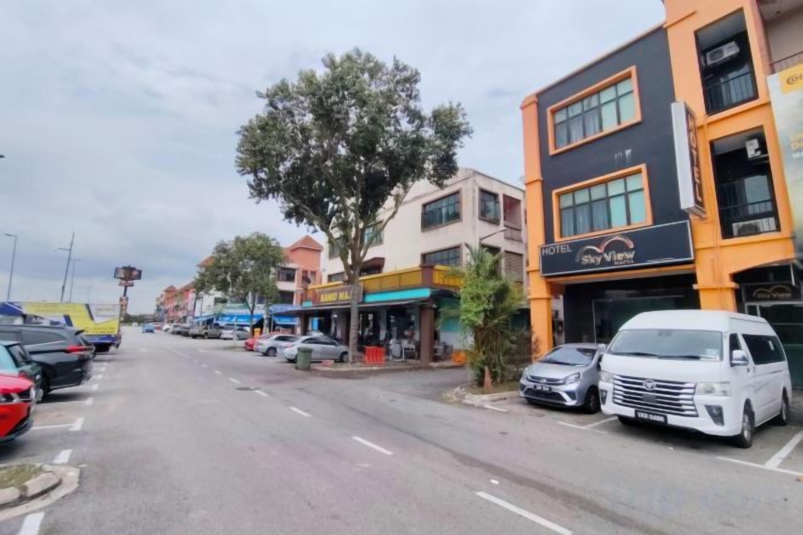 A street view with a hotel named 'Sky View' on the right, a tree-lined sidewalk, and parked cars.