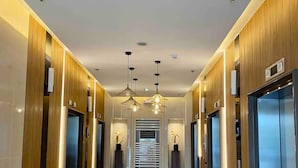 A modern hallway with wooden paneling, a marble floor, and a central elevator. - Shore 3 Residences by LUXE (Pasay)