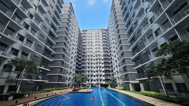 A modern apartment building with a central swimming pool surrounded by greenery. - Shore 3 Residences by LUXE (Pasay)
