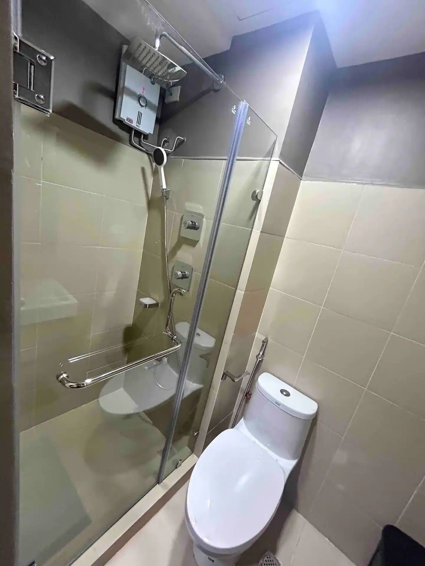 A bathroom with a glass-enclosed shower, a toilet, and a sink.