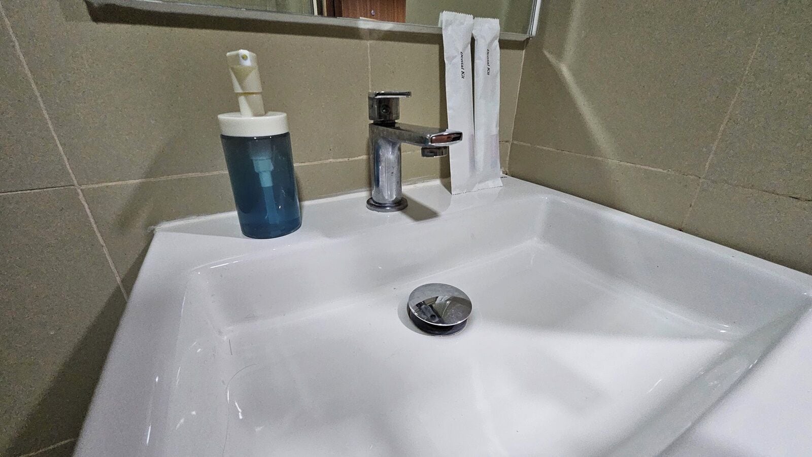 A bathroom sink with a blue soap dispenser, a faucet, and a towel rack.