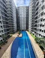 Ein modernes Apartmenthaus mit einem zentralen Schwimmbad, umgeben von Balkonen und Grünflächen.