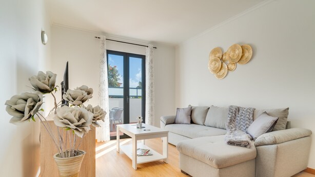 A modern living room with a grey sectional sofa, a white coffee table, and a vase with flowers.