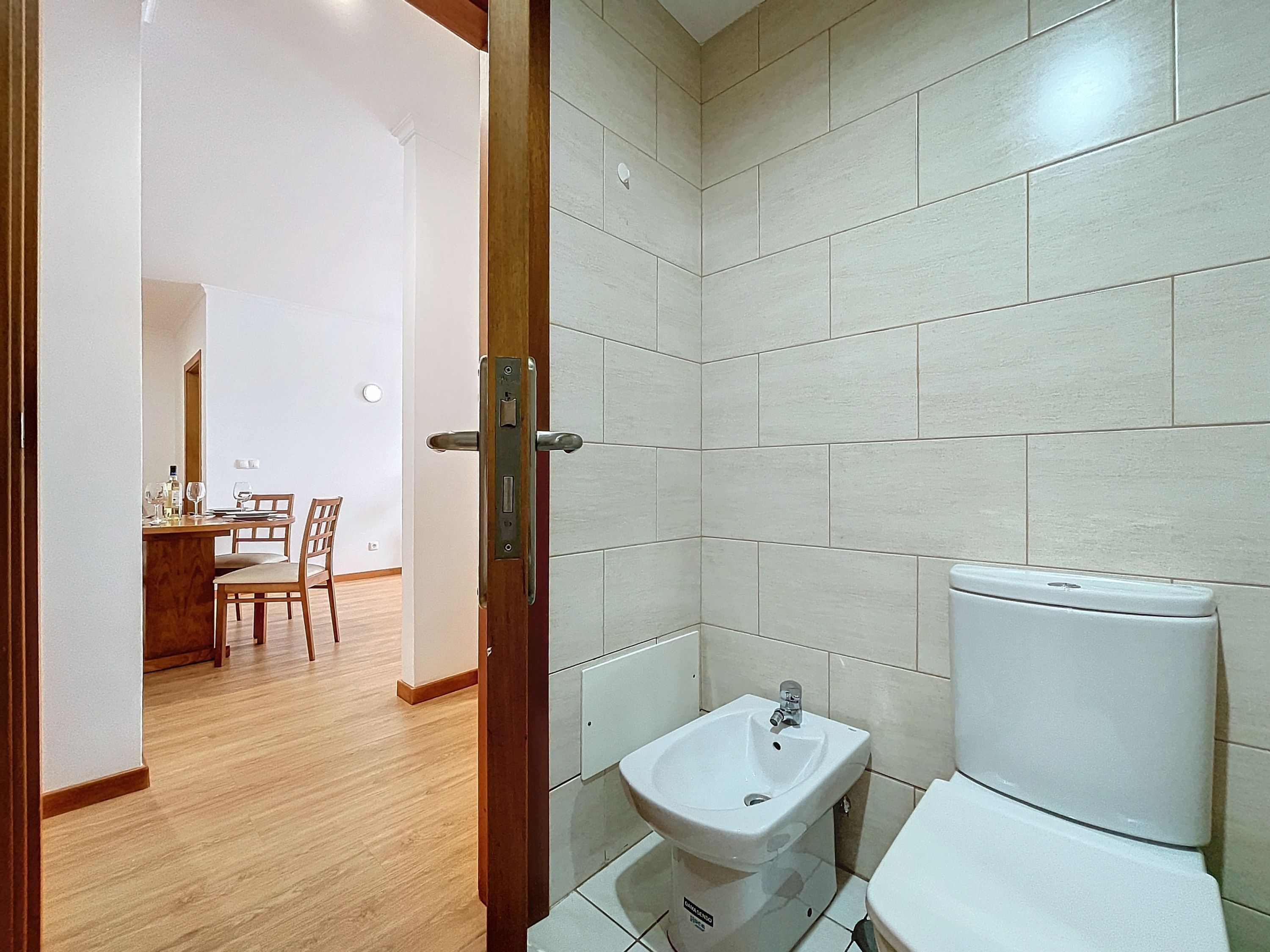 A bathroom with a toilet, sink, and tiled walls.