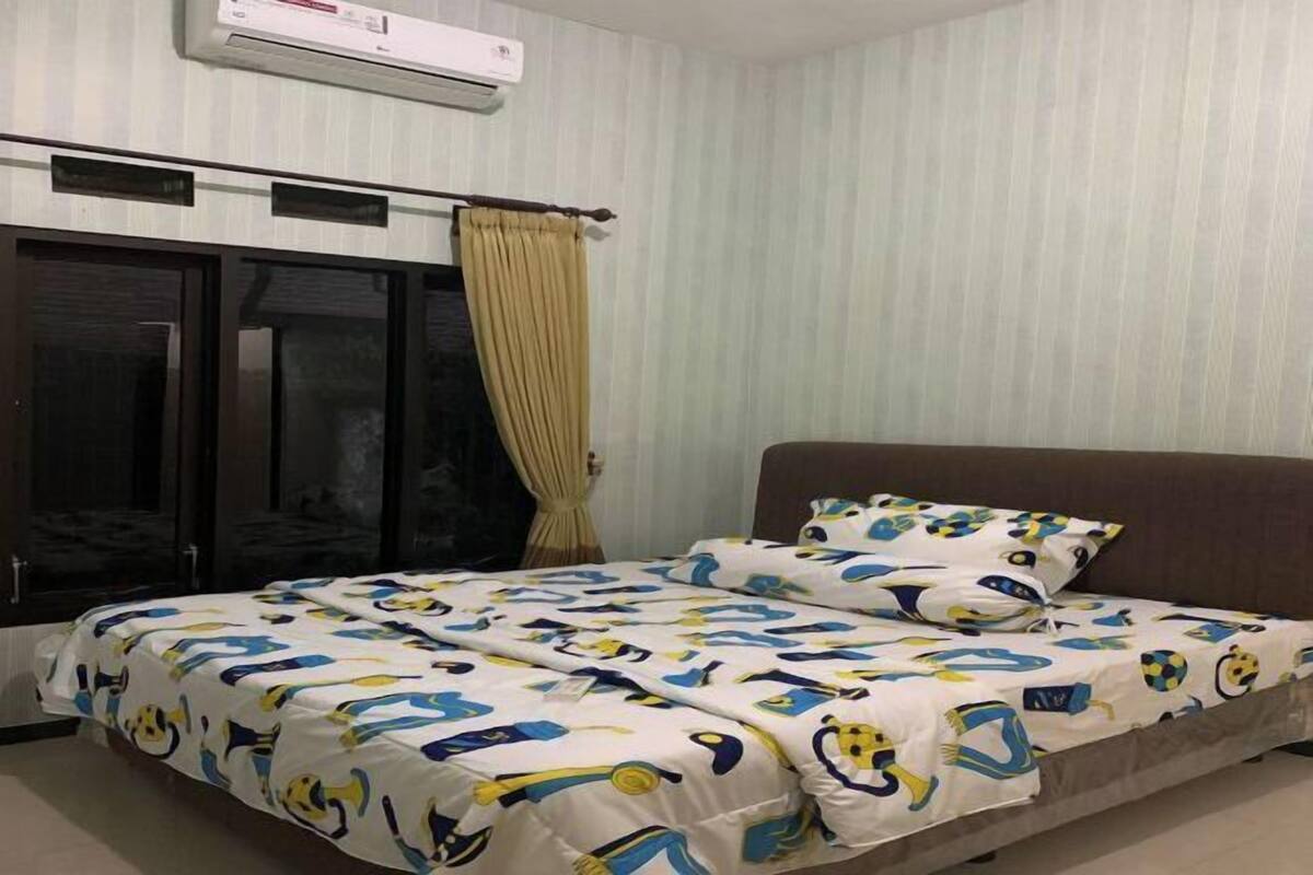 A bedroom with a bed, curtains, and an air conditioning unit.