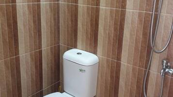 A bathroom with a toilet, a shower, and a wall with vertical stripes.