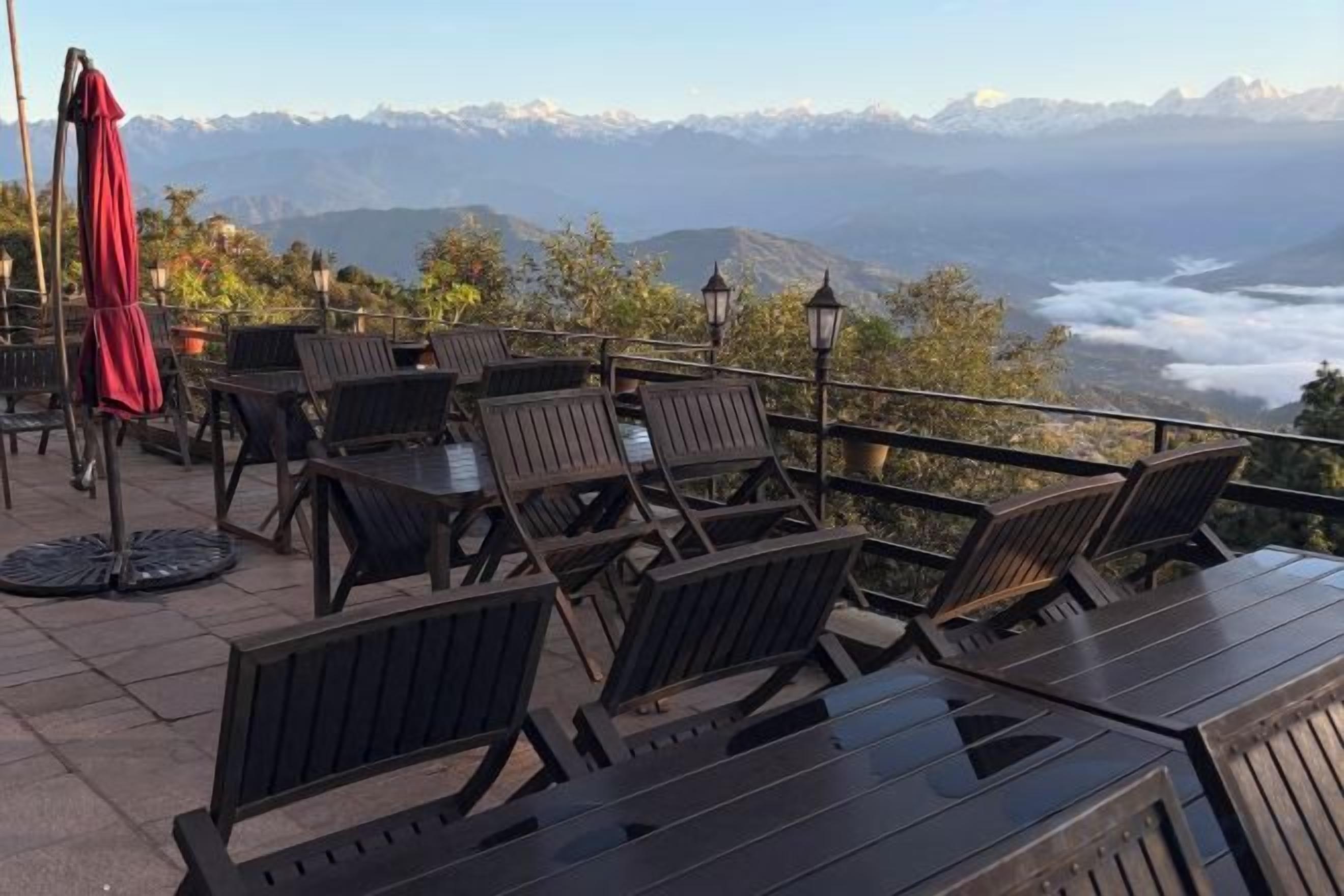 Un área de estar al aire libre con mesas y sillas, con vistas a un paisaje montañoso.