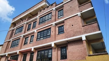 Un edificio de varios pisos con fachada de ladrillo, varios balcones y una sección inferior amarilla.