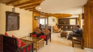 A spacious living area with wooden beams, a glass coffee table, and leather sofas. - Hotel green valley nagarkot (Baluwapati Deupur)