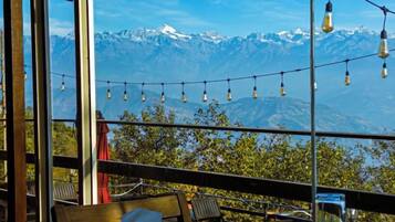 Una terraza con mesas y sillas, con vistas a un paisaje montañoso.