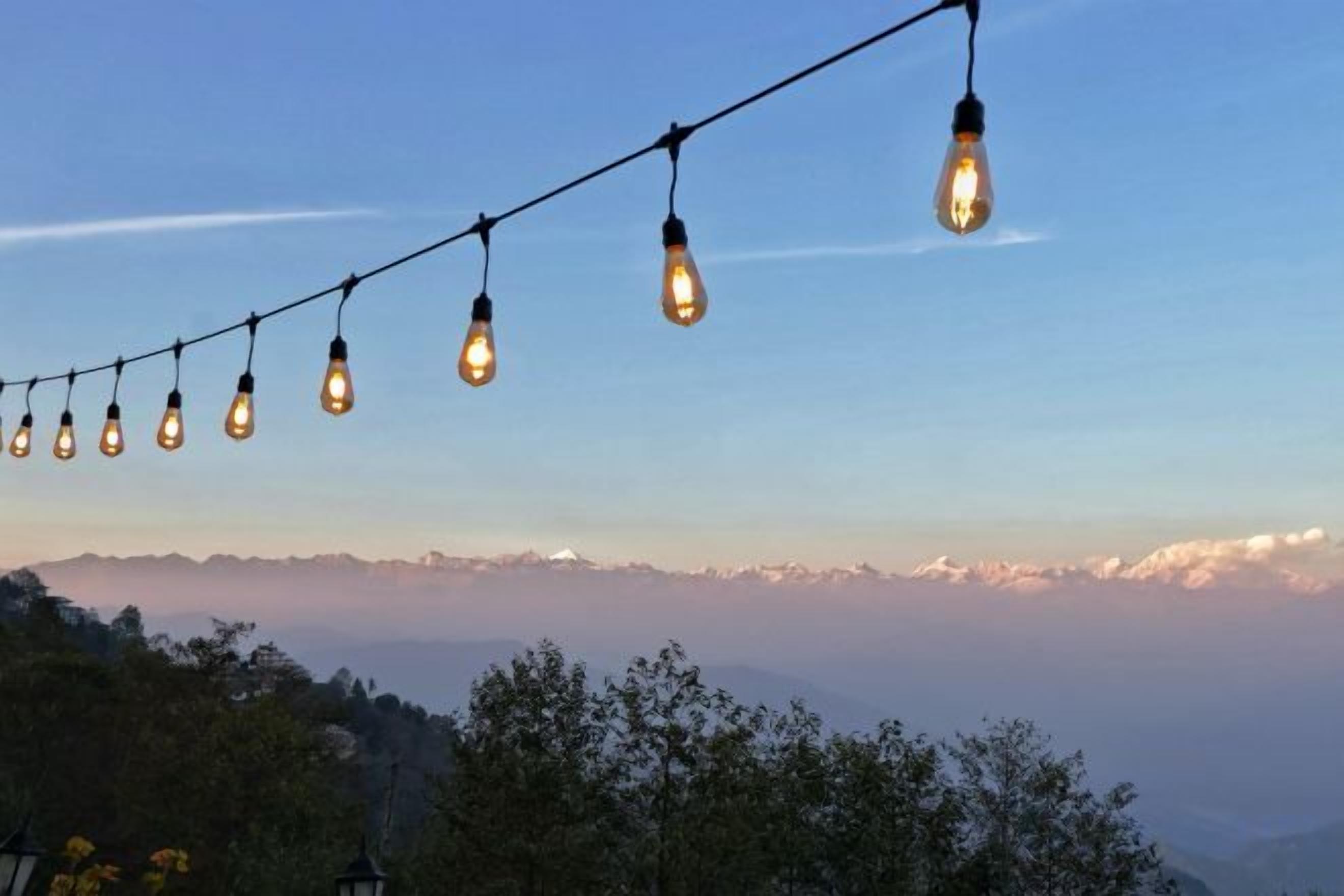 A string of light bulbs against a mountainous backdrop.