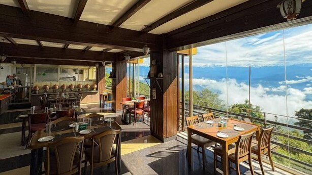 A restaurant with a mountain view, wooden interior, and multiple dining tables. - Hotel green valley nagarkot (Baluwapati Deupur)
