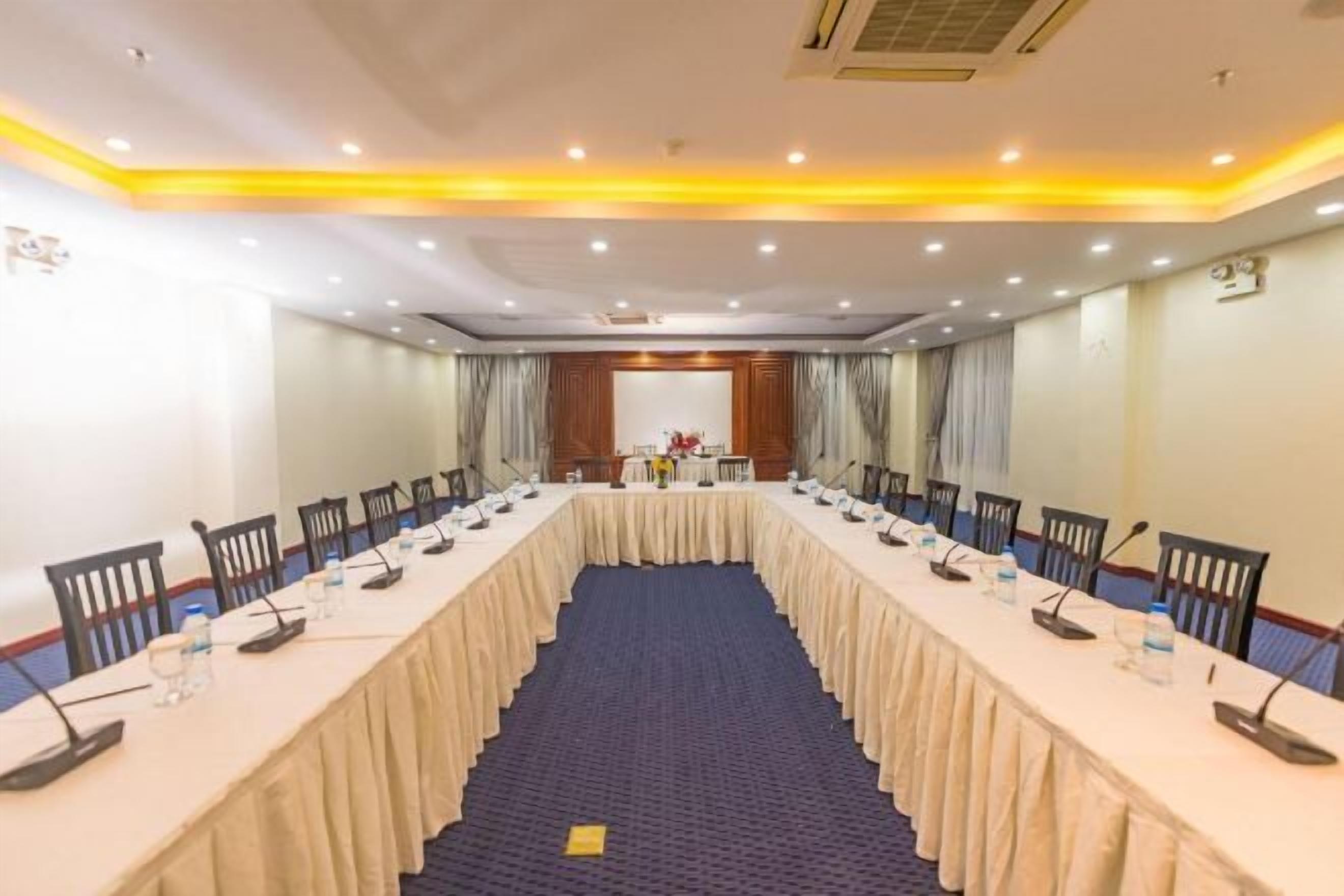 A conference room with a long table, chairs, microphones, and water bottles.