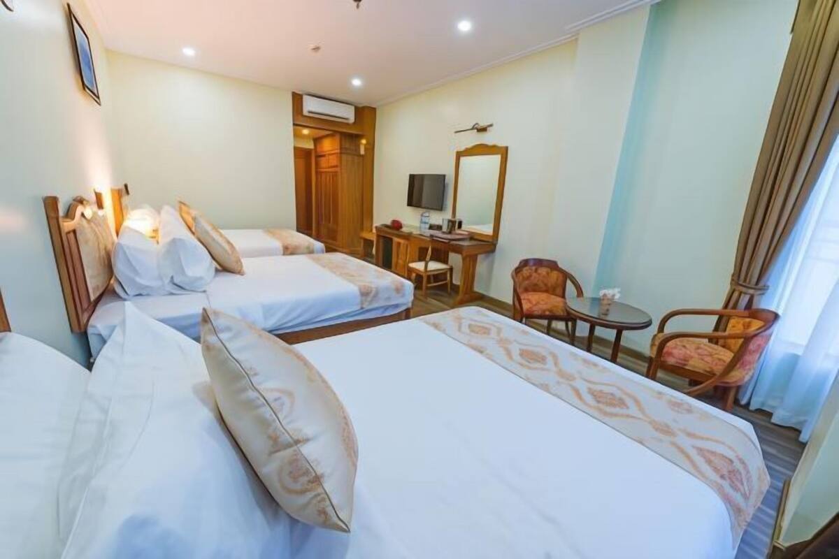 Une chambre d’hôtel avec deux lits, un bureau, une chaise et un téléviseur.