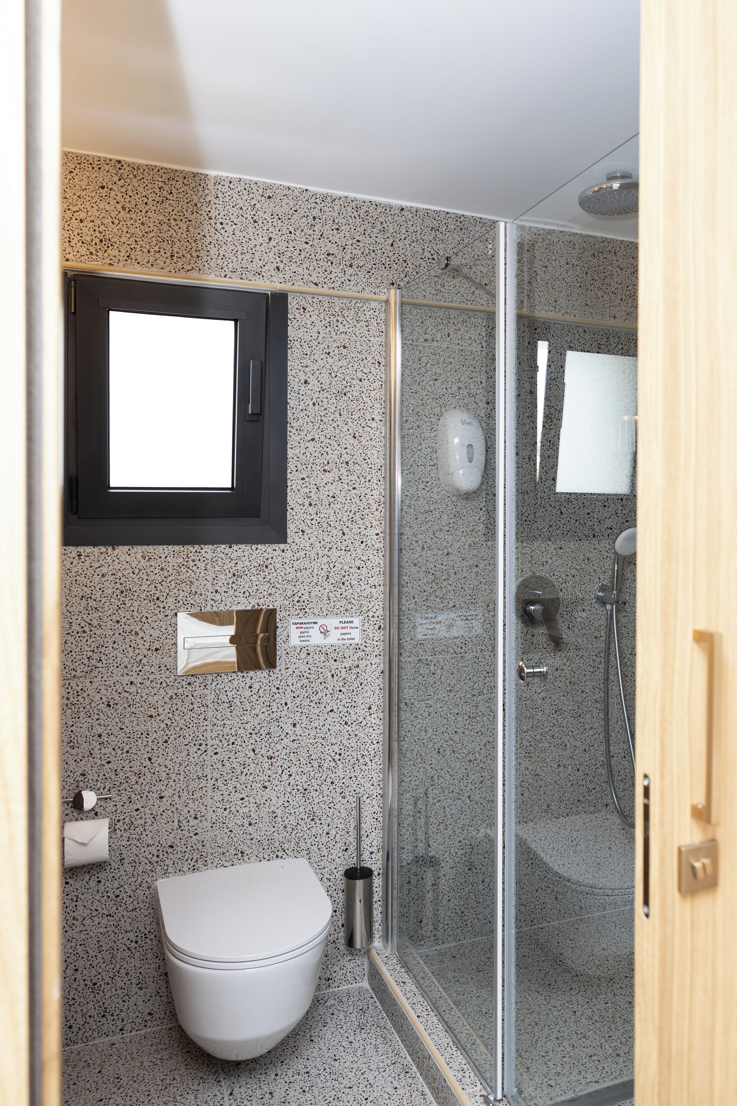 Une salle de bain moderne avec une douche à parois de verre, des toilettes, un distributeur de savon et un porte-serviettes.