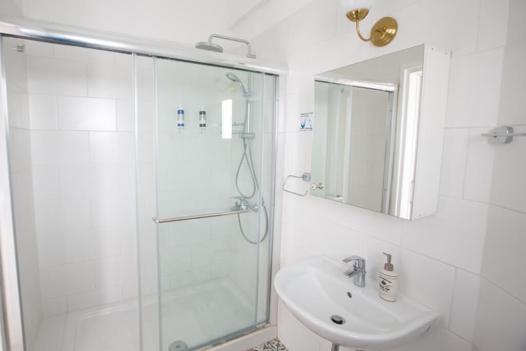A modern bathroom with a glass-enclosed shower, a white sink, and a mirror above it.