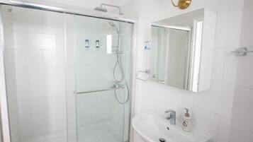 A modern bathroom with a glass-enclosed shower, a white sink, and a mirror above it.