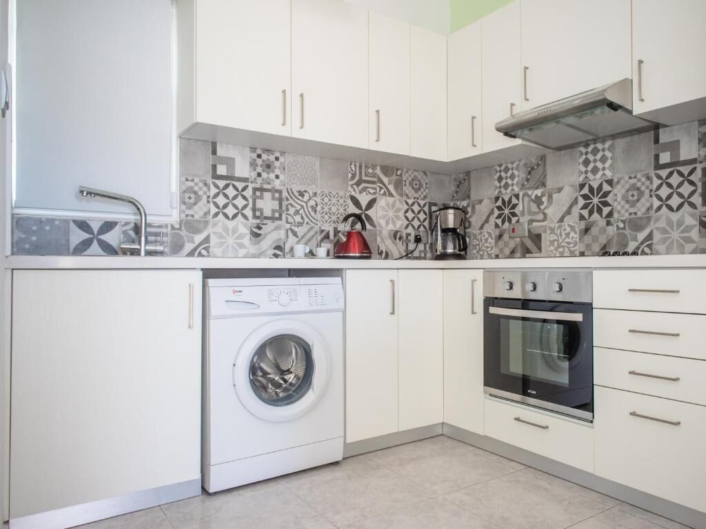 A compact kitchen with a washing machine, a coffee maker, and an oven.