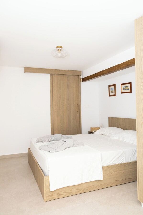 A bedroom with a wooden bed frame, a nightstand, and a wall-mounted light fixture.