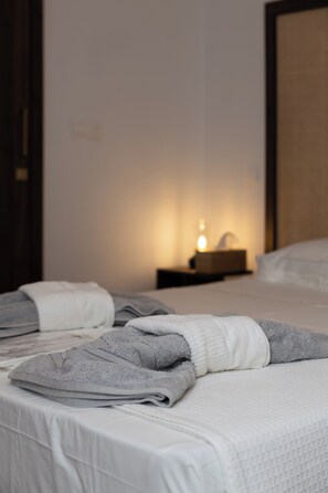 A hotel room with two beds, a bedside table with a lamp, and a nightstand with a tissue box. - PanMari Apartments (Paphos)