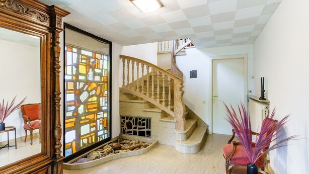 A staircase with a wooden handrail and a white wall with a door.