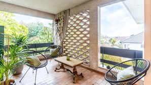 A balcony with a table and chairs, a potted plant, and a lattice screen.