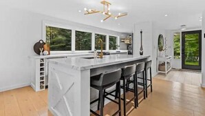 Een moderne keuken met een groot eiland, barkrukken en een bijzondere kroonluchter.