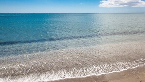 En strand med klart, lavt vand og en sandet kystlinje.