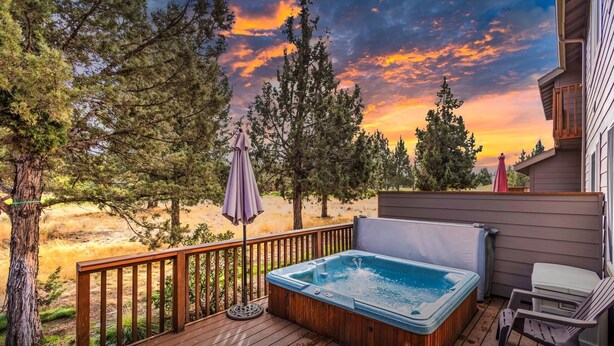 Eine Holzterrasse mit Whirlpool, einem Stuhl und einem Sonnenschirm.