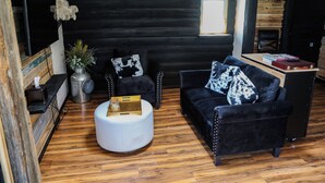 A modern living room with a black and white sofa, a round white ottoman, and a small table with books. - Colorado Cottage located at 7200 feet, near to Colorado Springs. (Elbert)