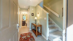 A hallway leading to a staircase with a carpeted floor and a small table with a lamp. - 2681 Forest Ridge B1 | 2BR Condo with Water Views (Fernandina Beach)