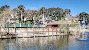 A waterfront park with a wooden deck, a fountain, and residential buildings in the background. - 2681 Forest Ridge B1 | 2BR Condo with Water Views (Fernandina Beach)