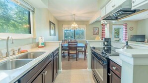 A kitchen with a dining area, stainless steel appliances, and a chandelier. - 2681 Forest Ridge B1 | 2BR Condo with Water Views (Fernandina Beach)