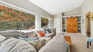 Ein Wohnzimmer mit großem Fenster, einer Couch, einem Holztisch und einem Schiebetürenschrank.