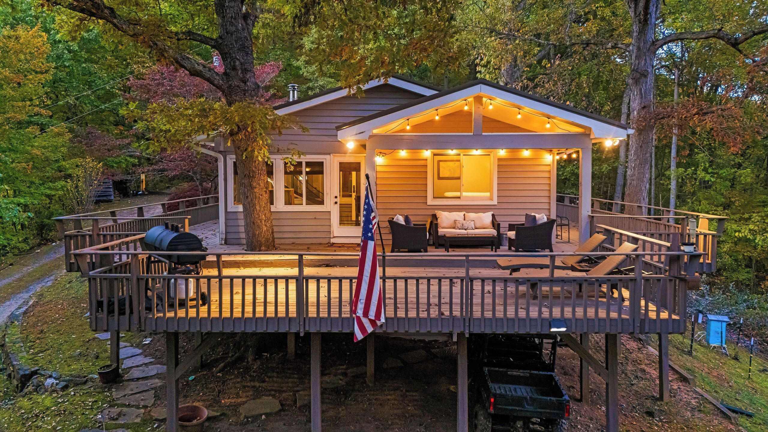 A cabin with a deck, outdoor seating, and a flag.