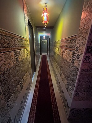 Stunning hallway with intricate tile patterns and a plush red carpet leading to a door.