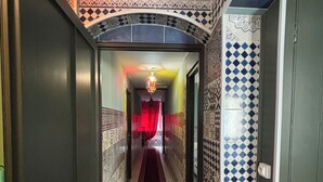 Un pasillo con paredes con diseño, alfombra roja y una lámpara colgante.