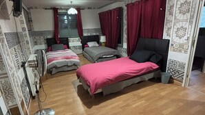 Un dormitorio con dos camas, un ventilador de pie y paredes con un diseño decorativo.