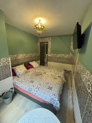 Cozy retreat with a patterned headboard, plush bed, and mounted TV.