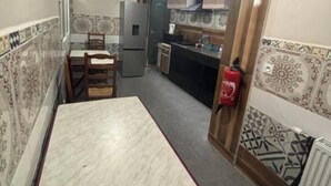 Una cocina compacta con una mesa de comedor y sillas, un refrigerador y un extintor.